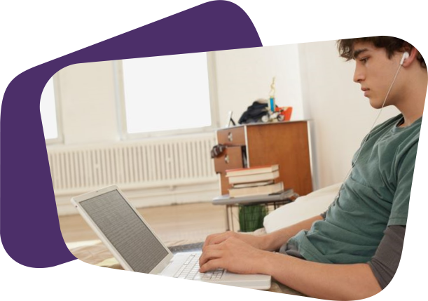 Teen boy studying on laptop in bedroom