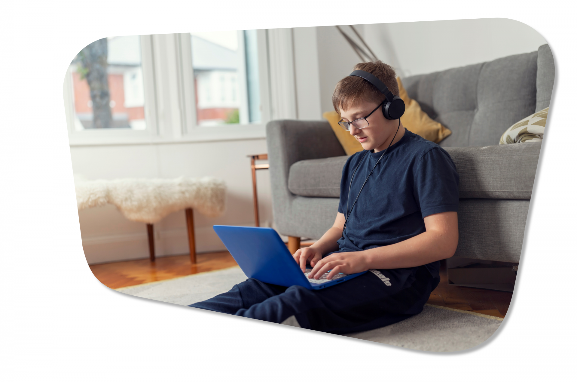 a picture of a teenaged boy, learning from home on a laptop wearing headphones. 
