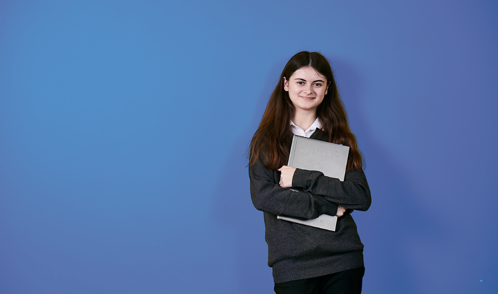 Female student with holds her laptop looking happy